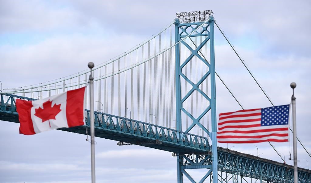 Canadian and American flags fly near the Ambassador Bridge at the Canada-USA border crossing in Windsor, Ont. on Saturday, March 21, 2020. THE CANADIAN PRESS/Rob Gurdebeke.